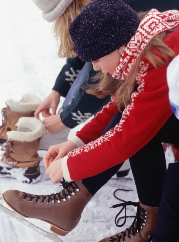 Young girl lacing up figure skates