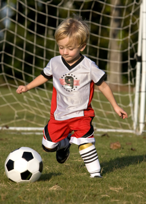 young child kicking soccer ball
