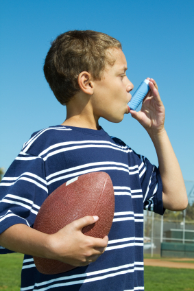 Boy using asthma inhaler holding football