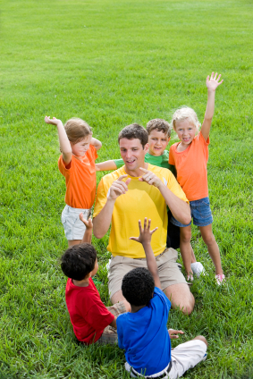 Camp counselor with kids on green lawn
