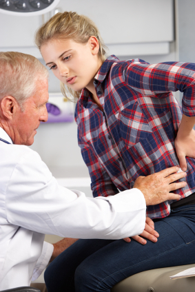Doctor examining teenage girl for back pain