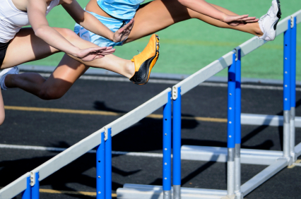 Female hurdlers clearing hurdles