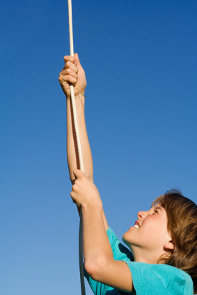 Girl climbing rope against blue sky