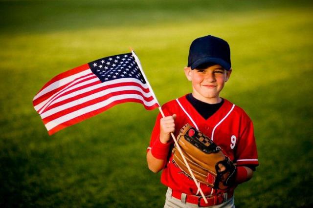 Young baseball player waving American flag
