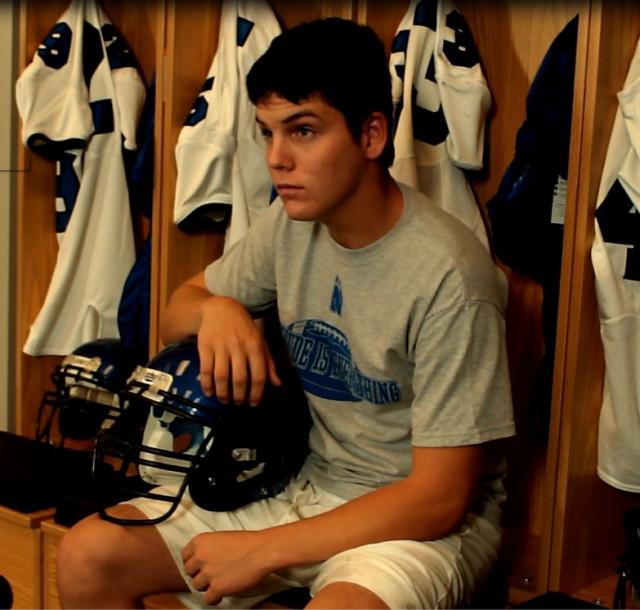 Teen football player sitting at locker
