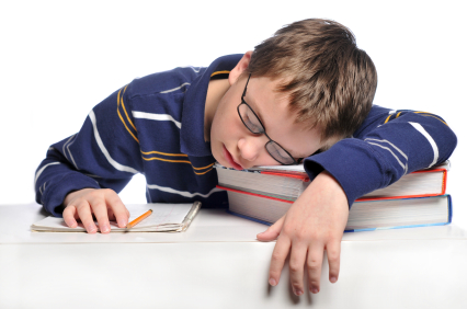 Pre-teen boy sleeping at desk with books