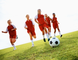 Group of young female soccer players chasing ball
