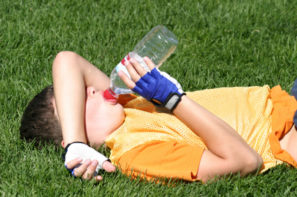 Tired soccer player drinking from water bottle