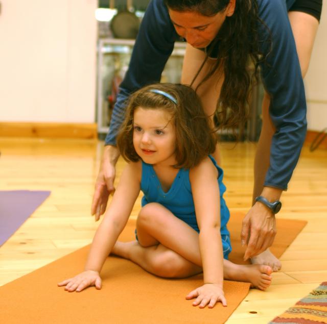 Yoga instructor helping young girl in pose