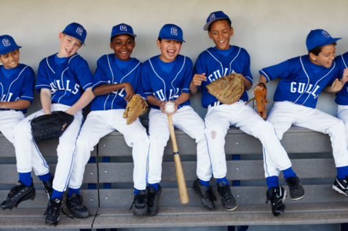 Youth baseball players laughing in dugout