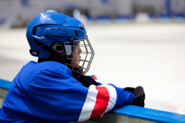 Youth hockey player on bench watching action