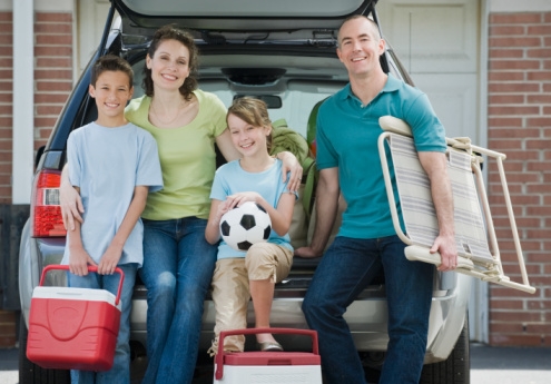 Sports parents in front of minivan with kids