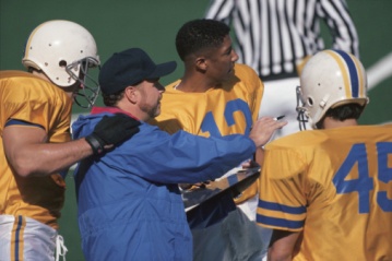 Football coach with players and referee in background