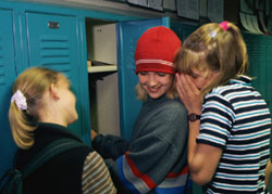 Teenage girls whispering at school locker