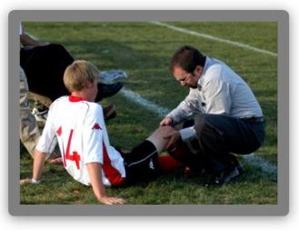Athletic trainer examining player's injured knee